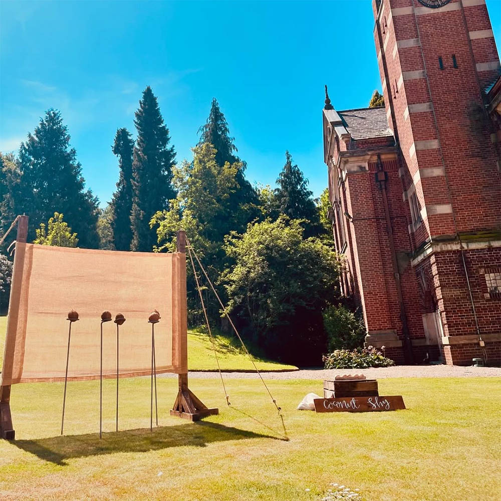 Coconut Shy: Traditional wooden Coconut Shy stall with vintage red and white bunting for outdoor event hire.