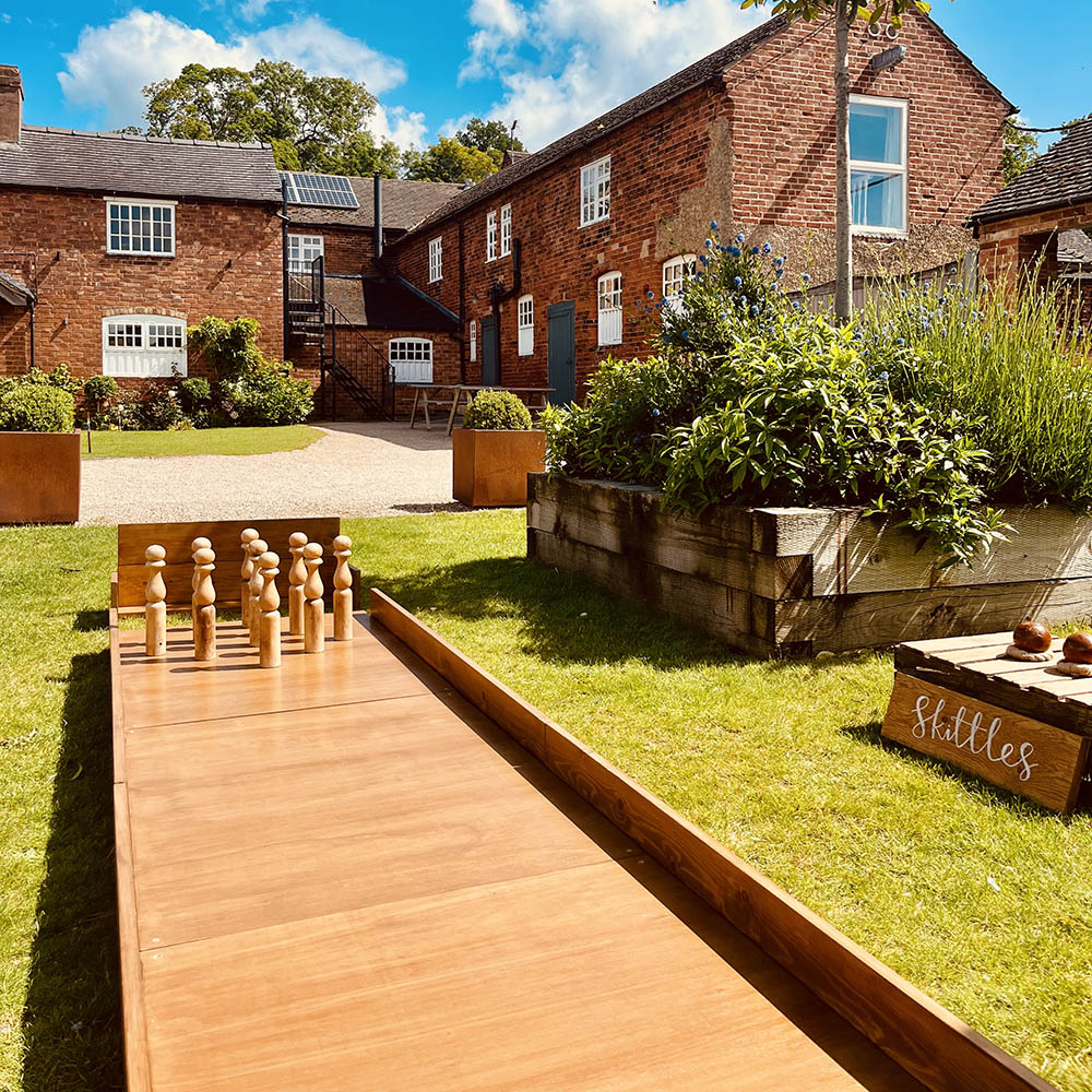 Skittles: Traditional wooden garden skittles and bowling balls set up on a flat grass surface for outdoor fun.