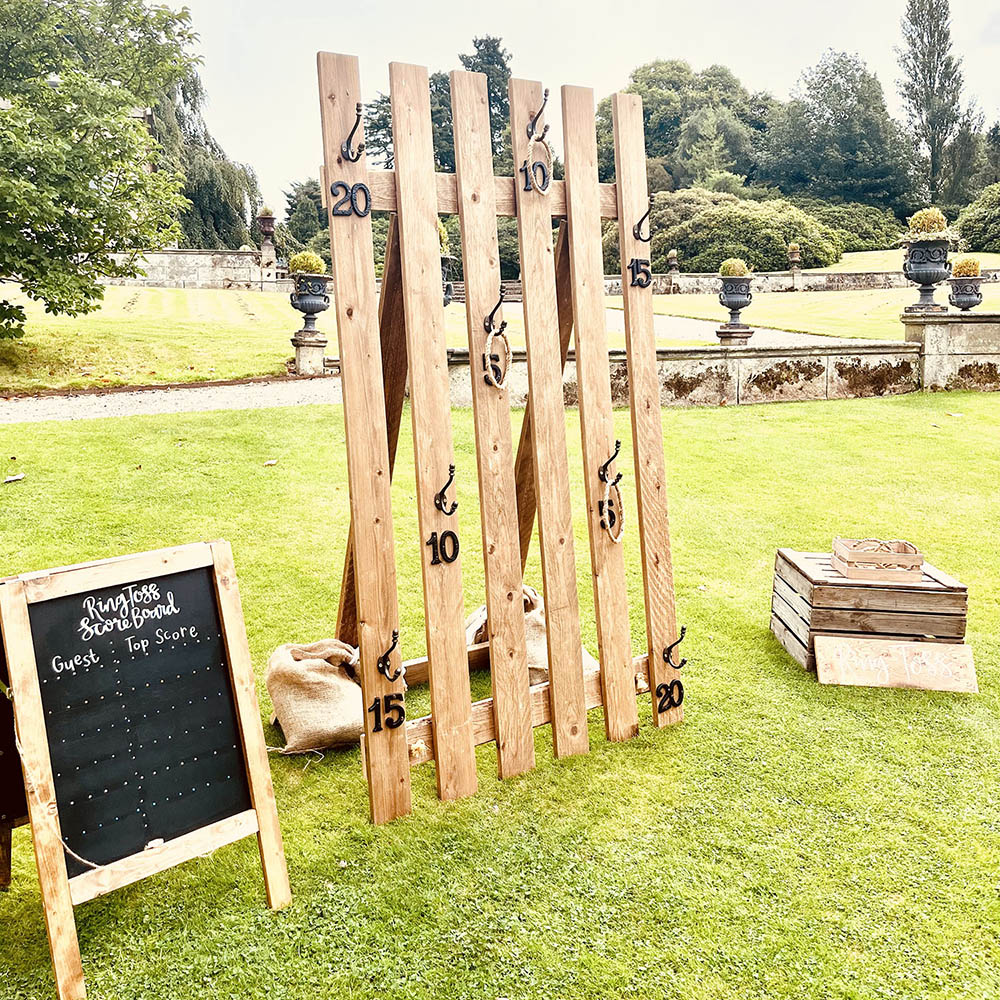 Ring Toss: Handcrafted wooden Ring Toss game with rope hoops, set up for a rustic wedding lawn by Pop Up Party UK.